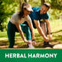 A young adult couple ties their shoelaces outdoors beside a green banner stating 'HERBAL HARMONY'.