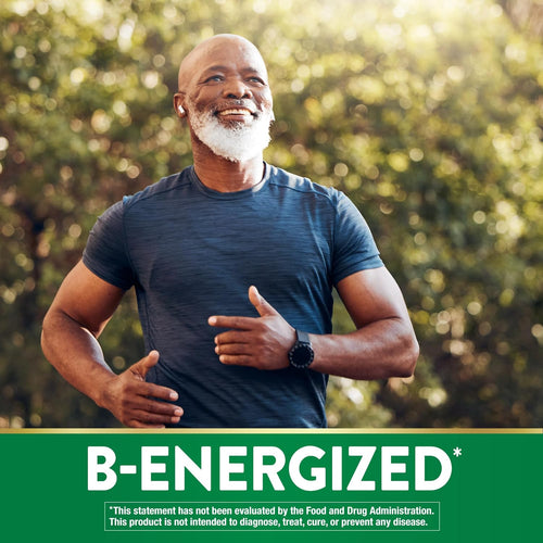 Older Black man jogging outdoors, smiling, wearing a blue shirt, wireless earbuds, and a smartwatch. Green trees in background.