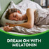 A young woman sleeps peacefully in bed with a bottle of Melatonin on the nightstand.