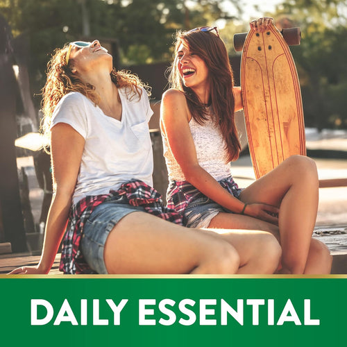 Two young women laughing and sitting outside; one holds a skateboard.