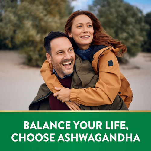 Smiling adult couple enjoying a piggyback ride outdoors. Text overlay reads: 'BALANCE YOUR LIFE, CHOOSE ASHWAGANDHA'.