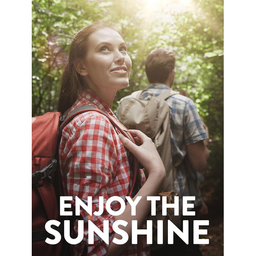 Young woman and man hiking in a forest, gazing up at sunlight streaming through the trees.