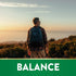 Middle-aged man with a backpack stands on a hilltop, admires a sunset over the ocean. Graphic at bottom reads 'BALANCE'.