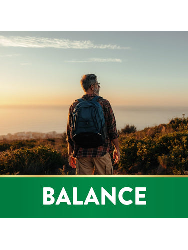Middle-aged man with a backpack stands on a hilltop, admires a sunset over the ocean. Graphic at bottom reads 'BALANCE'.