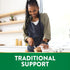 Young Black woman smiling and slicing bread in a kitchen, with a green banner at the bottom stating 'TRADITIONAL SUPPORT'.