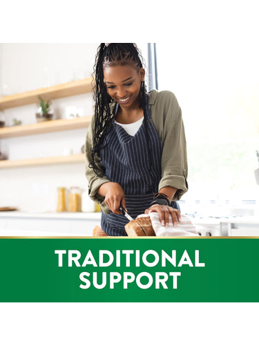 Young Black woman smiling and slicing bread in a kitchen, with a green banner at the bottom stating 'TRADITIONAL SUPPORT'.
