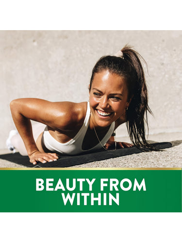 Young woman doing a push-up on a mat outdoors, smiling and sweaty, promoting Biotin.