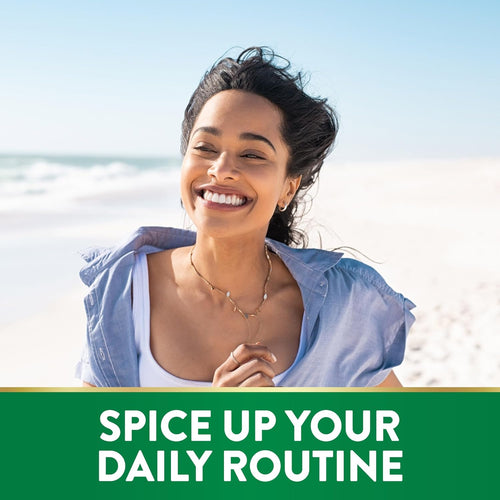 Young woman smiling with closed eyes, hair blowing in the wind at a sunny beach, conveying happiness and freedom.