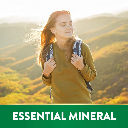 Woman with a backpack enjoys sunny mountain view with Magnesium Glycinate. Text: ESSENTIAL MINERAL.
