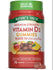 Hand holding two Vitamin D3 10,000 IU (250 MCG) gummies on a bulk scale.
