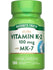 Vitamin K-2 100 mcg with MK-7 Quick Release Softgels on a hand scale, showcasing the size and quantity in bulk.