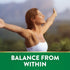 A young woman smiles with arms outstretched outdoors, with 'BALANCE FROM WITHIN' text at the bottom.