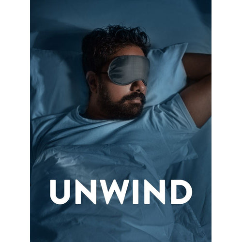 Man sleeping in bed with a grey sleep mask labeled 'UNWIND'. Promotes melatonin use.