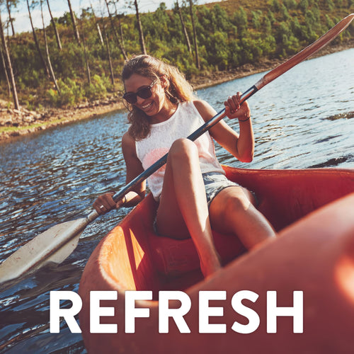 Young woman kayaking on a lake, smiling in sunglasses. Trees line the far shore. Text overlay: REFRESH.