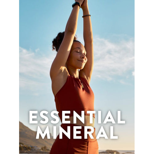 Young adult woman with eyes closed, arms stretched overhead, practicing yoga outdoors under a blue sky. Overlaid text: ESSENTIAL MINERAL.