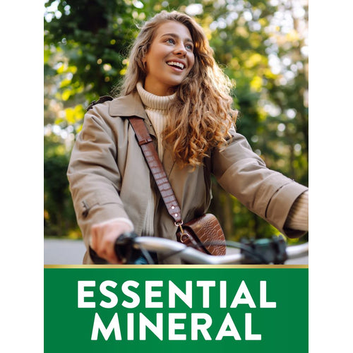 Young woman smiling while riding a bicycle outdoors, with a green banner showing 'ESSENTIAL MINERAL', NT Magnesium.