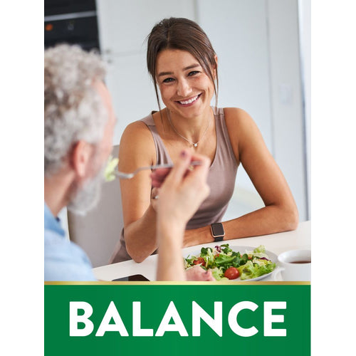 A smiling young woman and an older man share a salad at a table. A green banner at the bottom states 'BALANCE'.