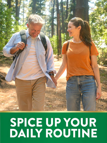Middle-aged couple hiking in a forest, holding hands and smiling with turmeric.