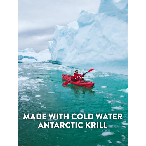 Adult kayaking in icy Antarctic waters near a large iceberg. Text: MADE WITH COLD WATER ANTARCTIC KRILL.