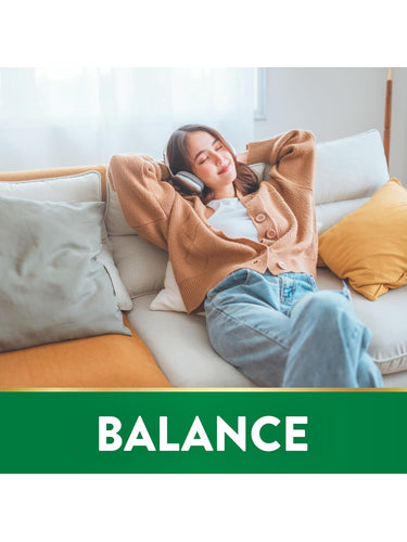 Young woman relaxing on a couch with headphones, eyes closed, smiling. The image includes the word 'BALANCE'.