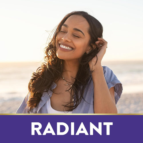 Young woman smiling, eyes closed, touching her hair on a beach at sunset. Text reads 'RADIANT.'