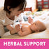 An adult woman smiling and interacting with a baby on a blanket, with the text 'HERBAL SUPPORT' visible.