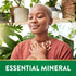 A young woman with eyes closed, hands on heart, stands in a plant-filled room with the text 'ESSENTIAL MINERAL'.