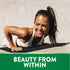 Young woman doing a push-up on a mat outdoors, smiling and sweaty, promoting Biotin.