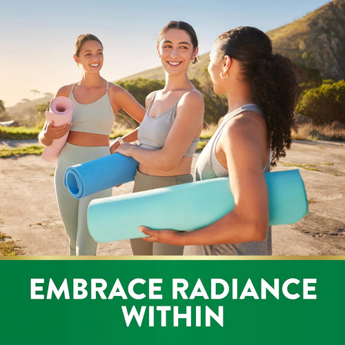 Three young adult women are smiling and walking outdoors while holding yoga mats.