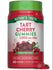 A hand holding a bottle of Tart Cherry 2,000 MG equivalent gummies, with a notable balance of supplements seen in the scale.