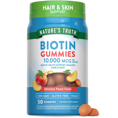 Two peach-colored Biotin gummies resting on a hand scale.