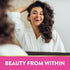 Young woman in white bathrobe smiling while touching her curly hair. Text: BEAUTY FROM WITHIN.