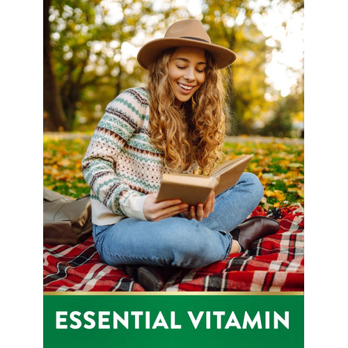 Young woman outdoors on a plaid blanket, smiling and reading a book, with text 'ESSENTIAL VITAMIN'.