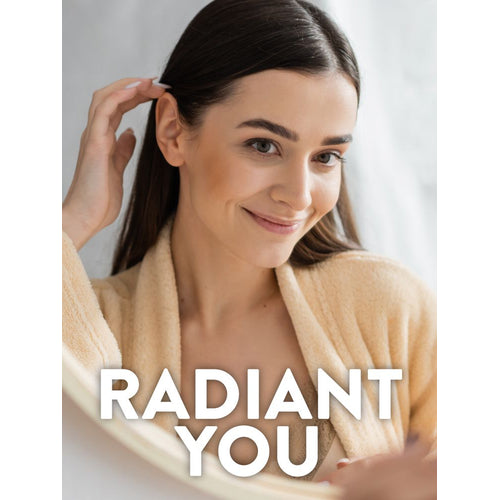 Young adult woman in a beige robe looking into a mirror, smiling and touching her hair. Text overlay reads 'RADIANT YOU'.