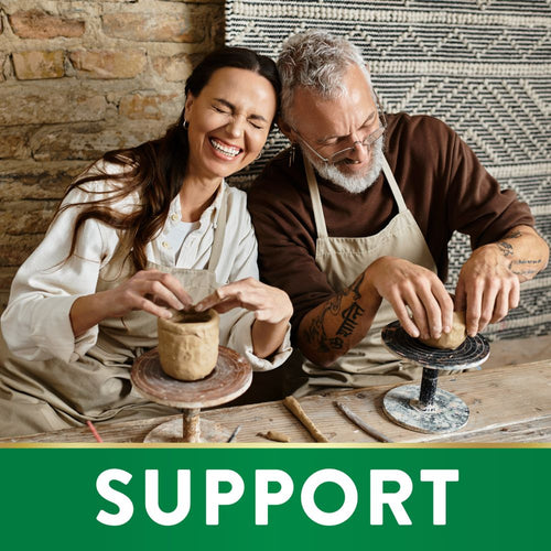 A man and woman smile while making pottery, with an overlay of the word 'SUPPORT'.