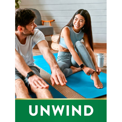 Young man and woman sitting on yoga mats, smiling and stretching. Green banner below reads UNWIND.