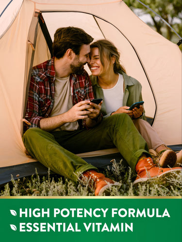 Young couple in a tent, smiling with phones, displaying text: HIGH POTENCY FORMULA ESSENTIAL VITAMIN.