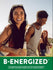 A young woman smiles, holding a 'B-ENERGIZED' bottle, while friends socialize outdoors.