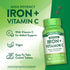 A pair of dark grey, round, coated tablets containing 65 mg of Iron plus Vitamin C, displayed on a hand scale.