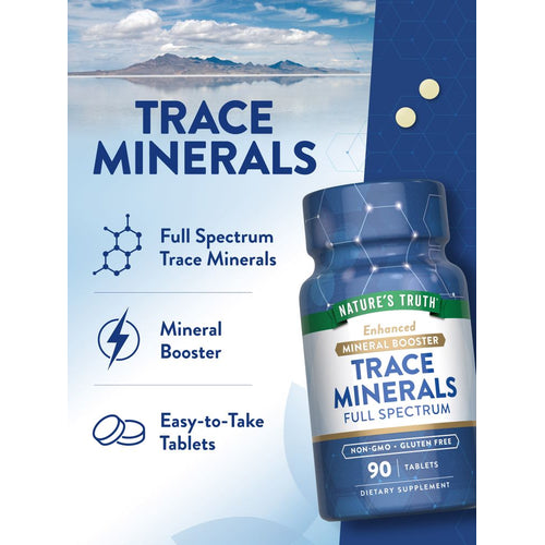 A hand holds two light yellow round Trace Minerals tablets on a bulk scale.